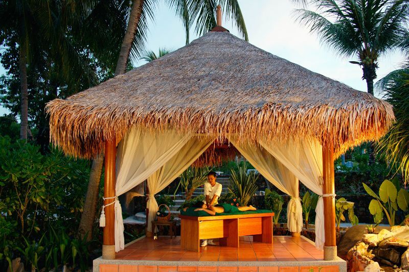 Massage in tropical spa. A young woman having a back massage outside in tropical setting.