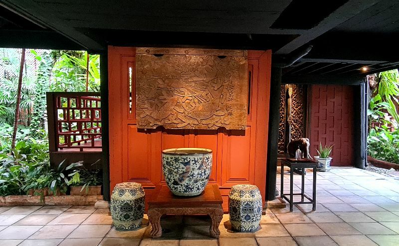 a large ceramic pot placed on a wooden stand, flanked by two smaller ceramic stools.